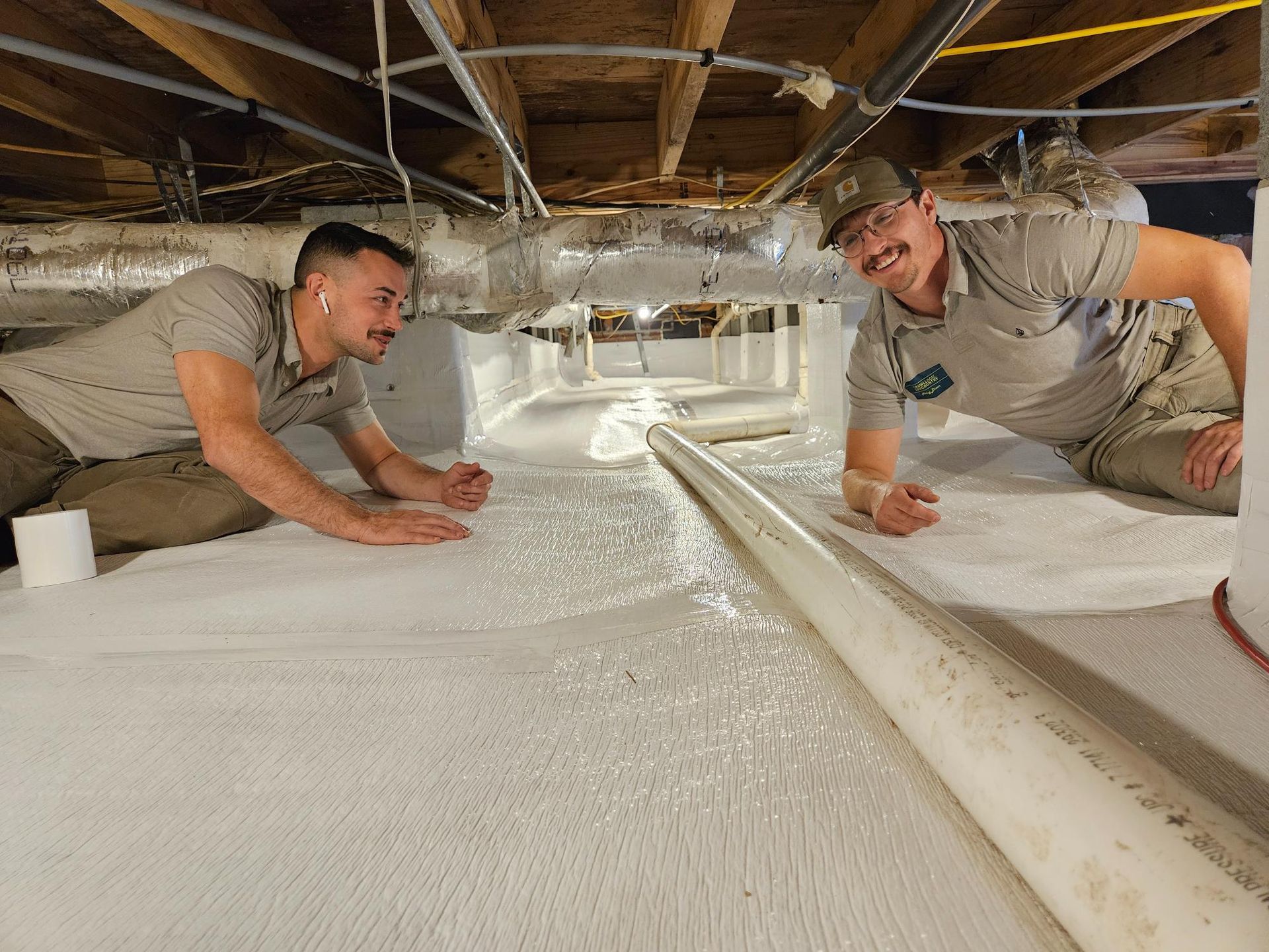 Two men are kneeling on the floor of a basement.