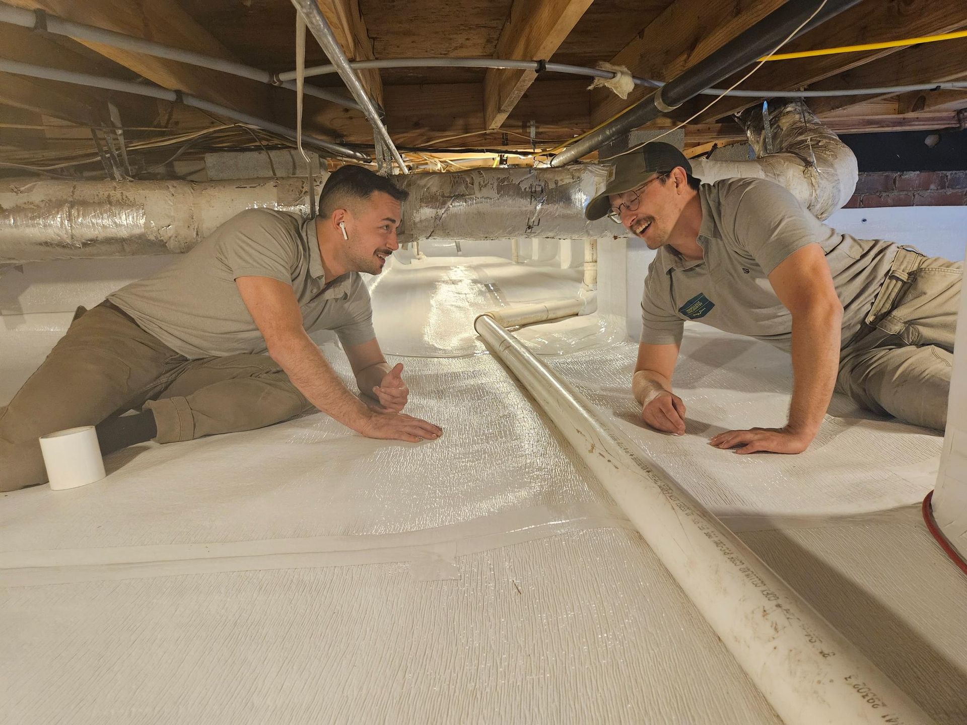 Two men are kneeling on the floor of a basement.