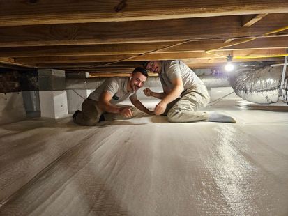 Two men are kneeling on the floor of a basement.