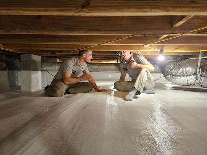 Two men are kneeling on the floor of a basement.