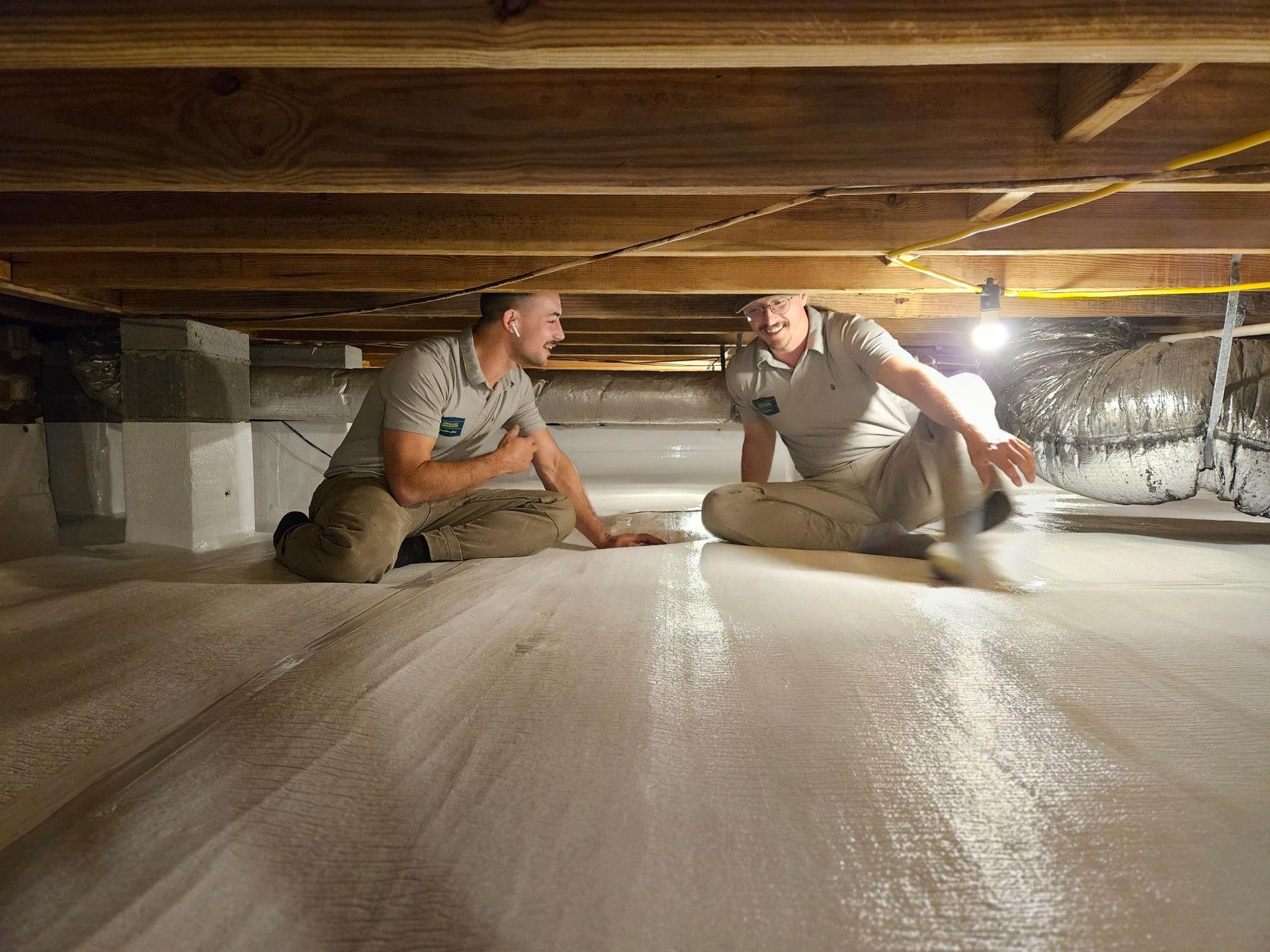 Two men are kneeling on the floor of a basement.