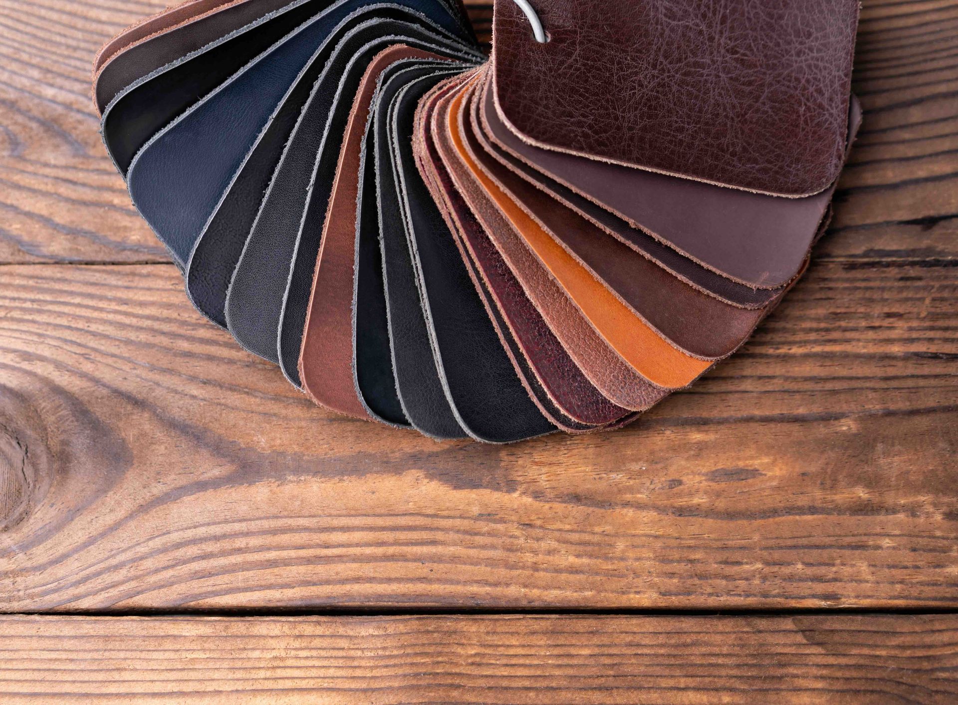 A bunch of different colored leather samples on a wooden table.