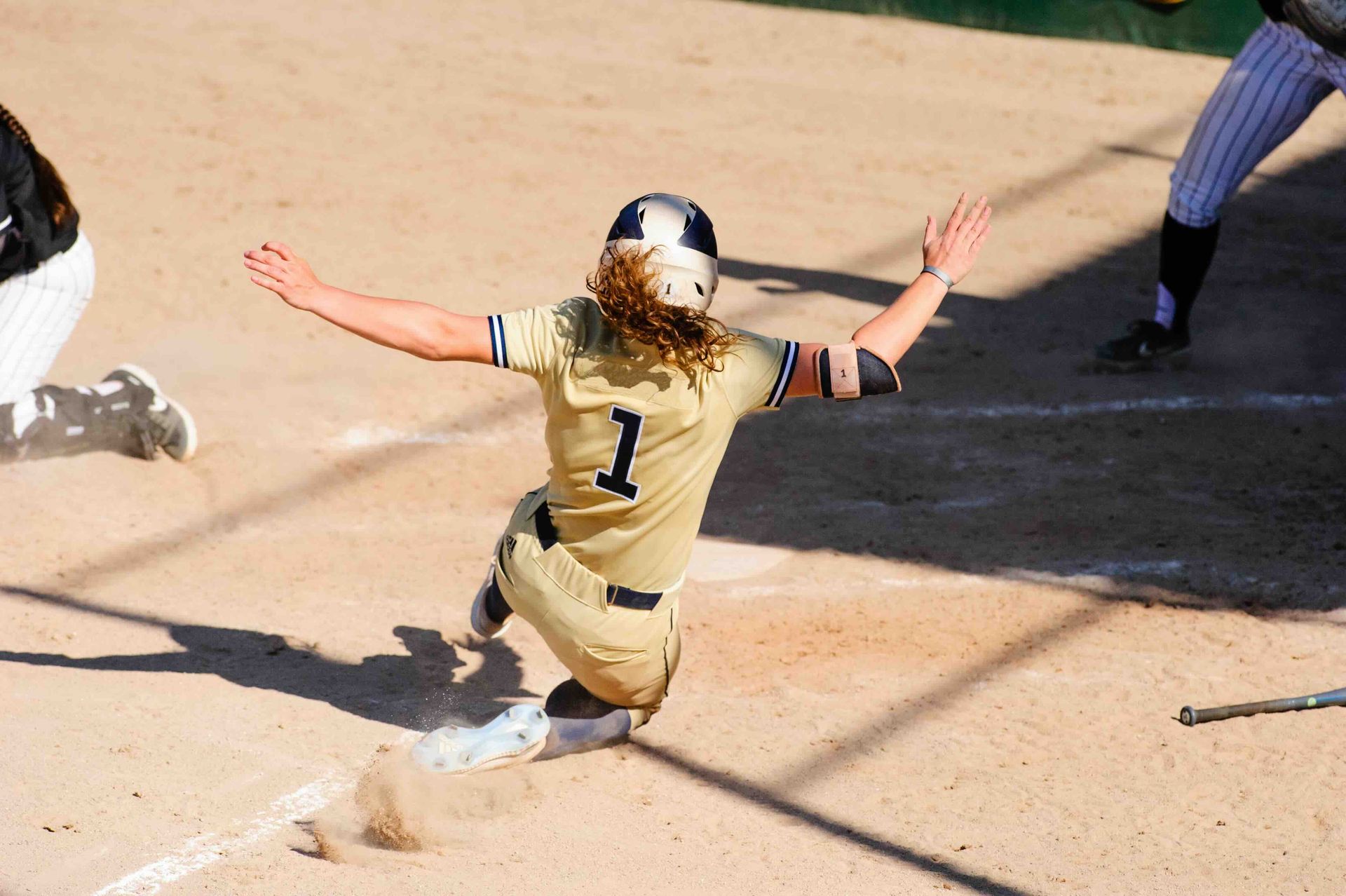 A woman is sliding into home plate during a softball game.