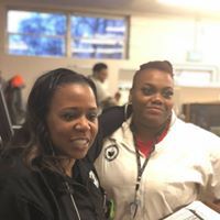 Two women are standing next to each other in an office and smiling.