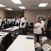 A group of people are standing around tables in a room.