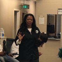 A woman is standing in a waiting room with people sitting in chairs.