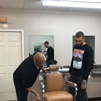 Two men are standing next to a barber chair in a barber shop.