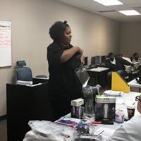 A woman is standing in front of a group of people in a classroom.