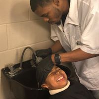 A man is washing a child 's hair in a sink.