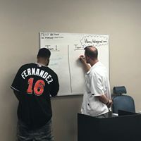 Two men are writing on a whiteboard in a room.