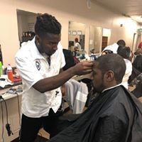 A man is getting his hair cut by a barber in a barber shop.