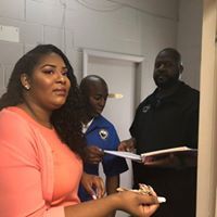A woman in a pink shirt is standing next to two men in a room.