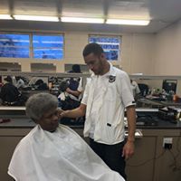 A man is giving an older woman a haircut in a barber shop.