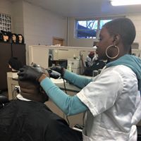 A woman is blow drying a man 's hair in a salon.