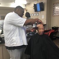 A man is getting his hair cut at a barber shop.
