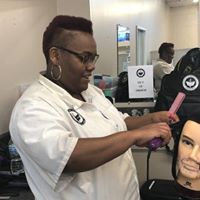 A woman is cutting a mannequin 's hair in a salon.