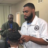 A man with a beard is cutting a man 's hair in a barber shop.