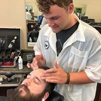 A man is getting his beard shaved by a barber in a barber shop.