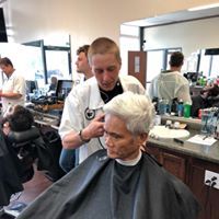 An older woman is getting her hair cut by a barber in a barber shop.