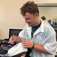 A man is cutting a man 's hair in a barber shop.