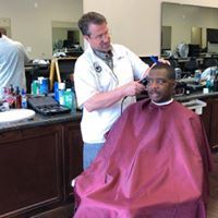 A man is getting his hair cut at a barber shop.