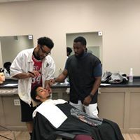 Two men are shaving a man in a barber shop.