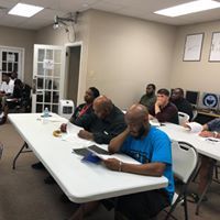 A group of men are sitting at tables in a room.