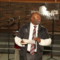 A man in a suit and tie is standing in front of a microphone.