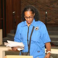 A woman in a blue shirt is holding a piece of paper.