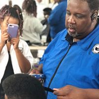 A man is cutting a child 's hair in a barber shop while a woman looks at her phone.