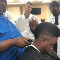 A group of men are getting their hair cut at a barber shop.