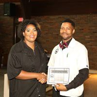 A man and a woman are shaking hands and holding a certificate.