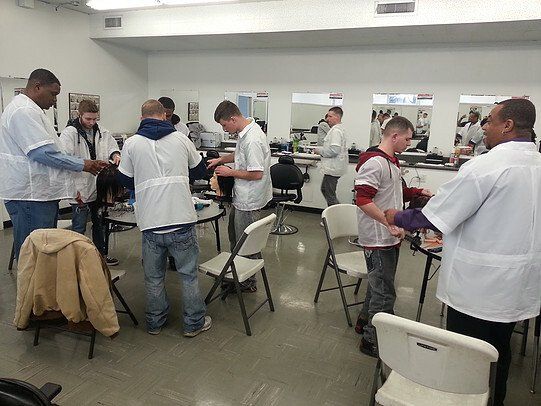 A group of people standing around tables and chairs in a room
