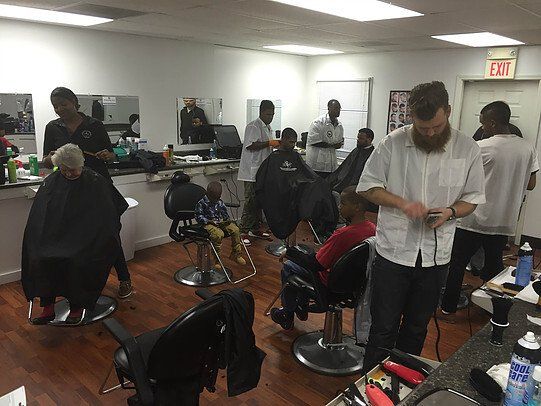 A group of people are getting their hair cut at a barber shop.