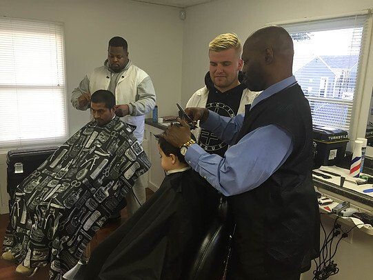 A group of men are getting their hair cut at a barber shop
