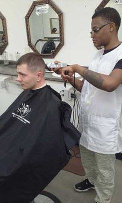 A man is getting his hair cut by a barber in a barber shop.