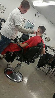 A man is getting his hair cut by a barber in a barber shop.