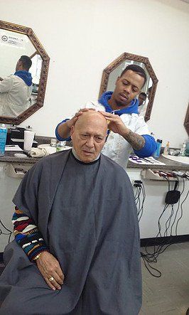 A man is getting his hair cut by a barber in a barber shop.