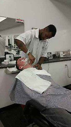 A man is getting his beard shaved by a barber in a barber shop.