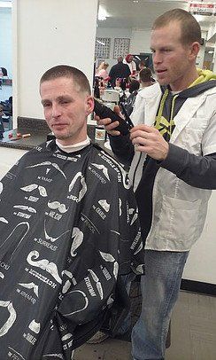A man is getting his hair cut by a barber in a barber shop.