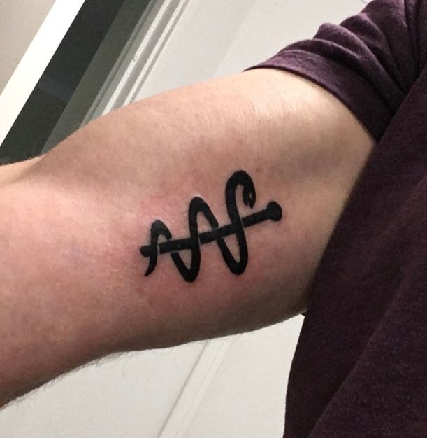 Close-up of an arm with a small black abstract tattoo near the elbow.