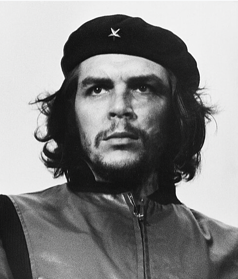 Black-and-white portrait of a man in a beret and zip-up jacket, looking straight ahead.