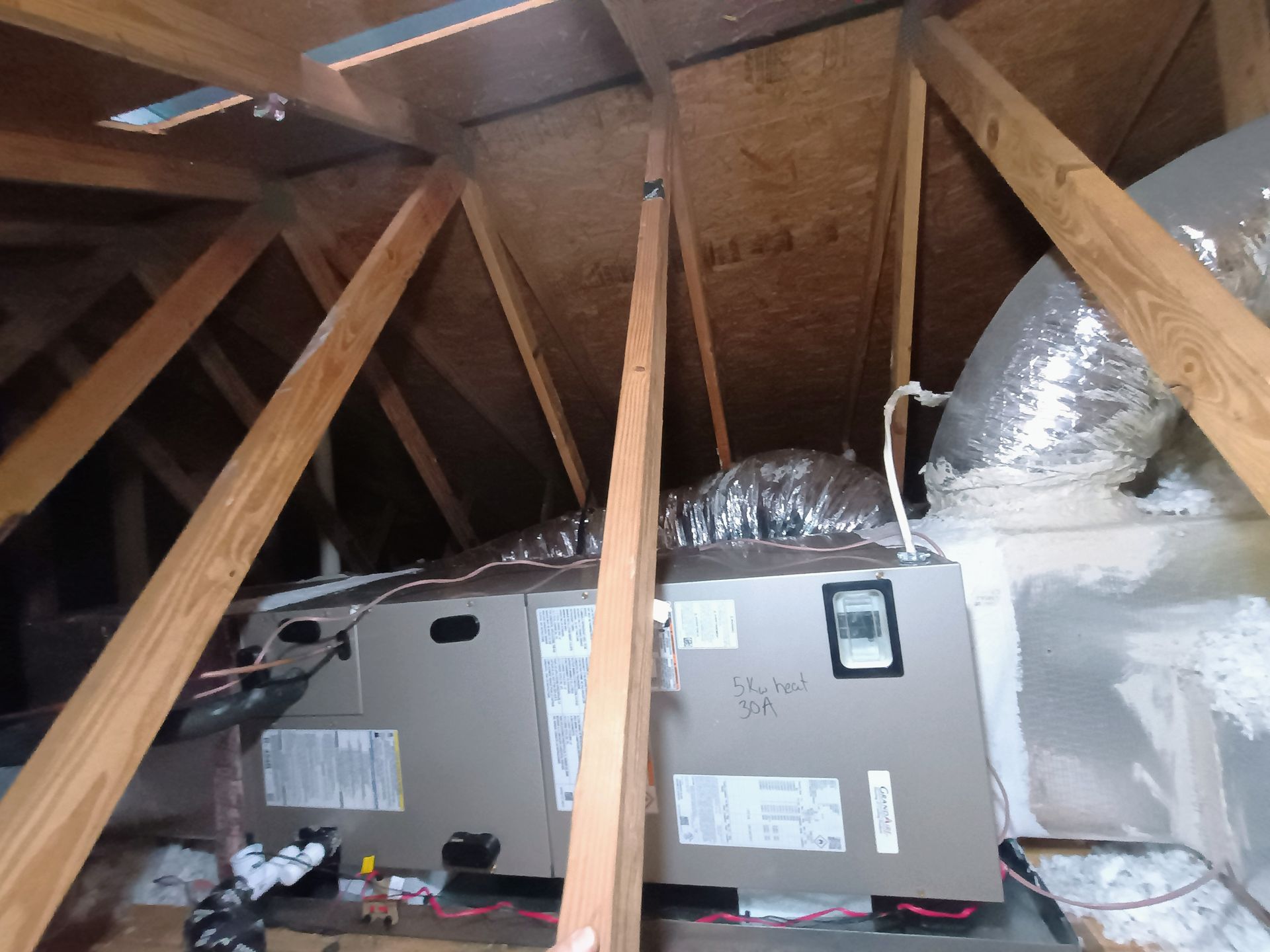Air conditioning unit mounted above a TV, supported by yellow bracing.