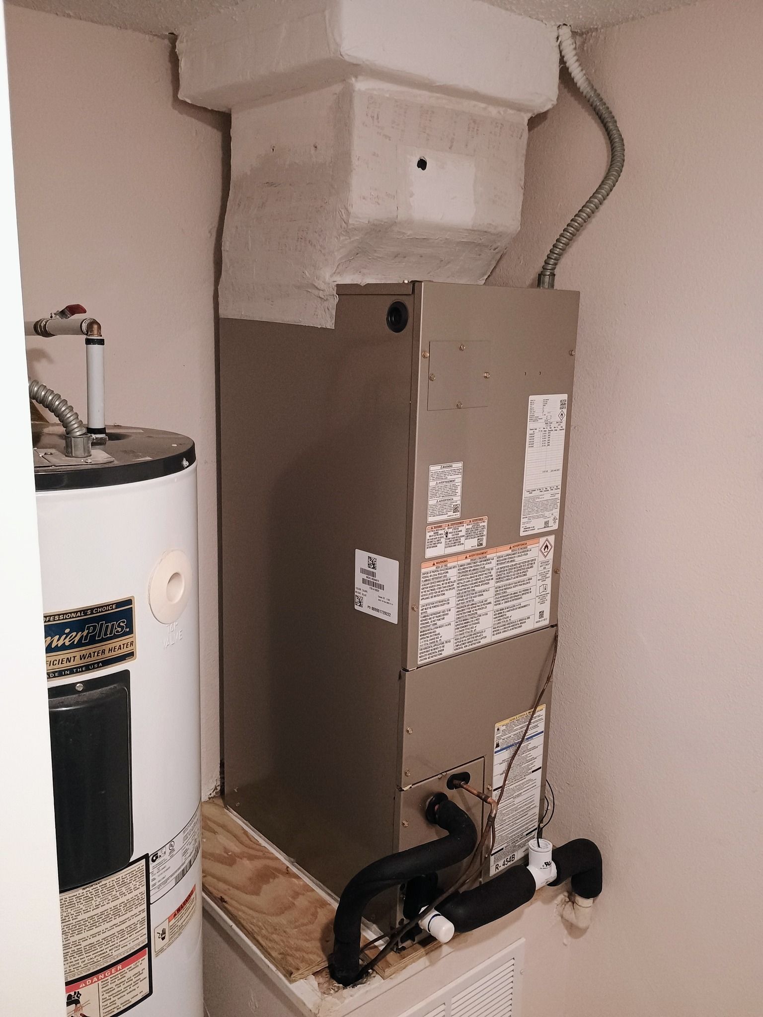 An indoor HVAC unit and water heater in a utility room.