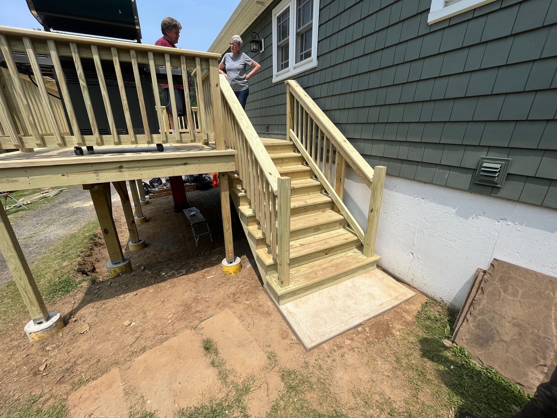 Wooden deck with stairs leading to ground level, people on deck.
