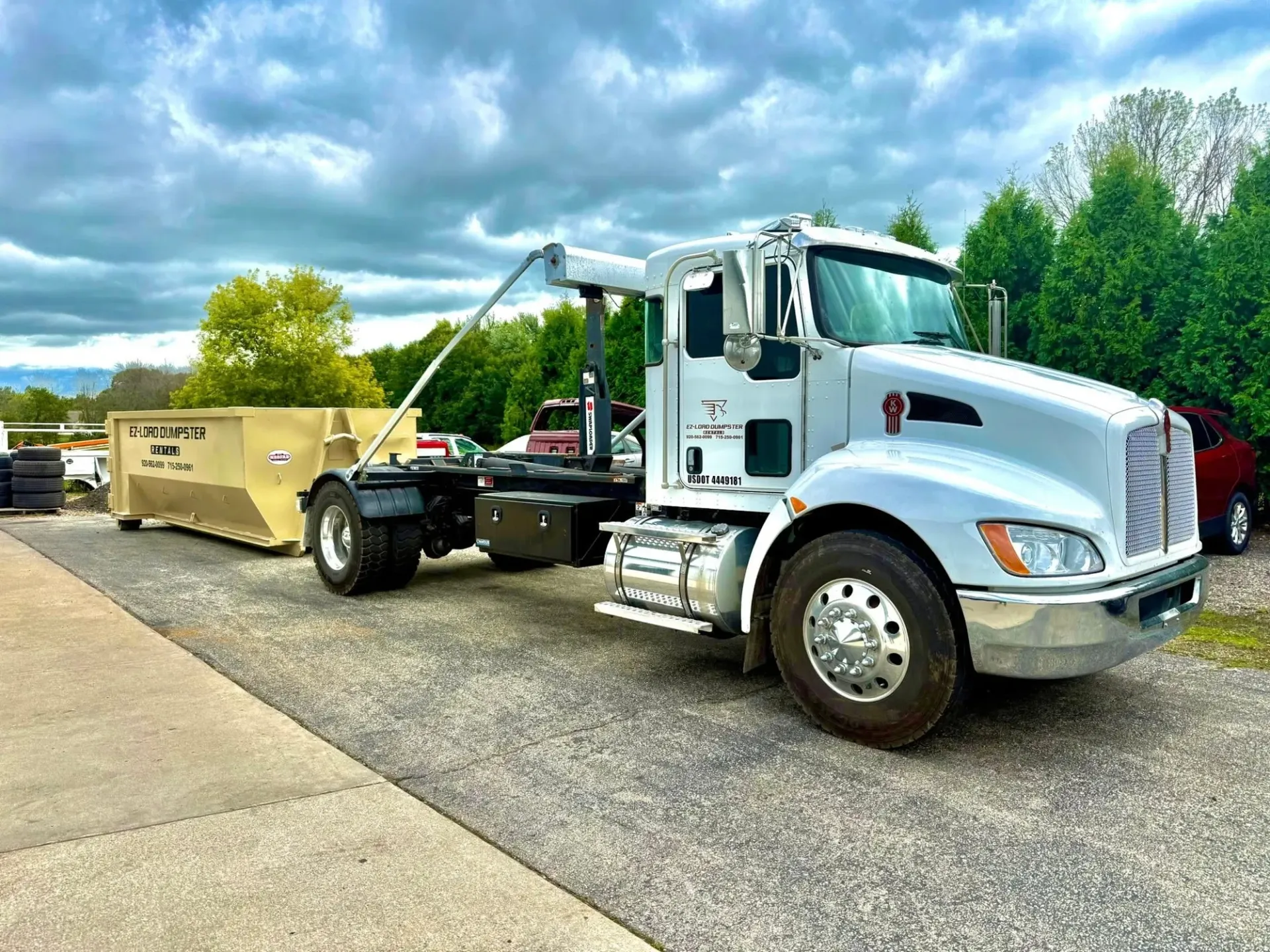 An aerial view of a dump truck driving down a road next to a body of water.