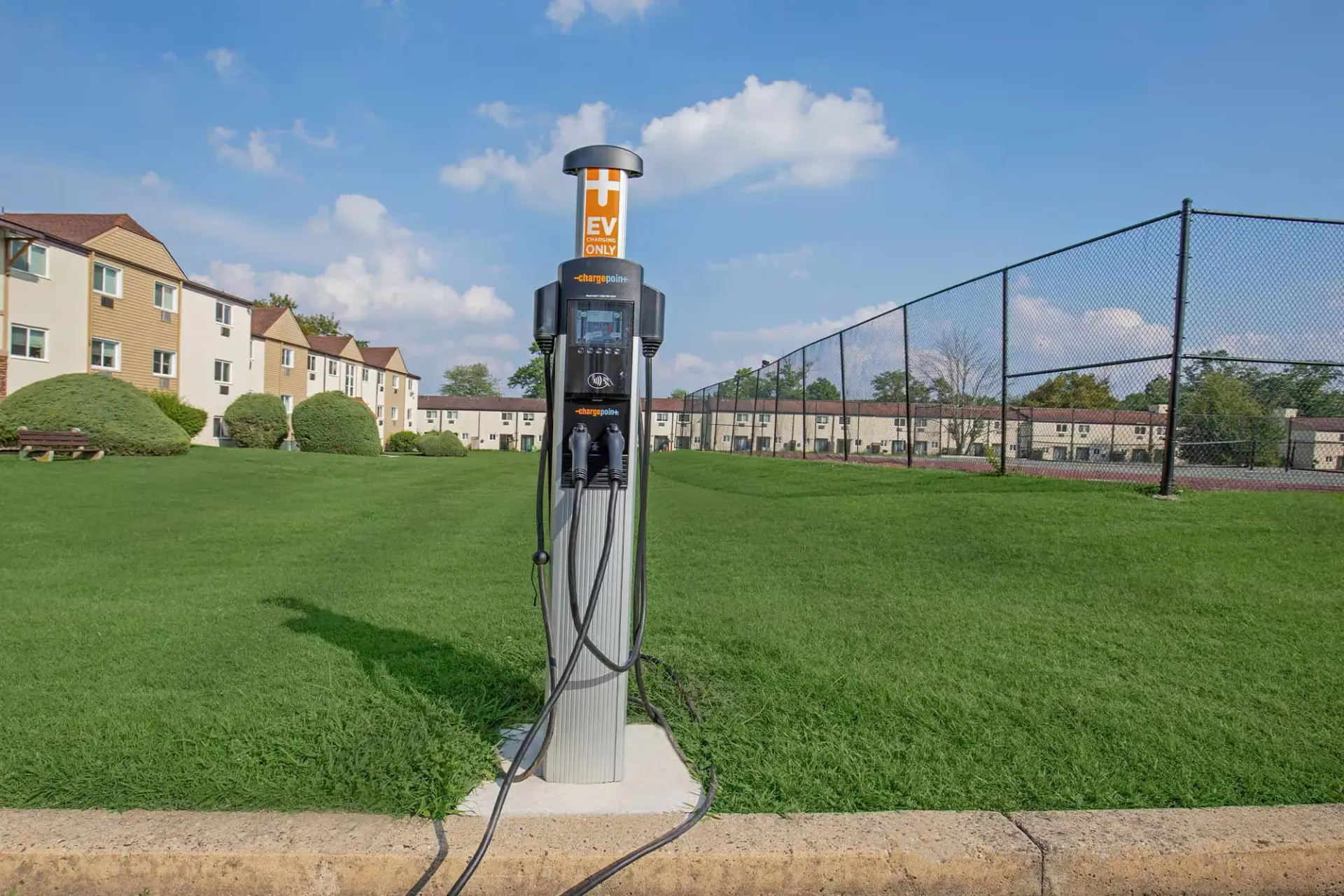EV charging station in a grassy communal area beside apartment buildings at The Addison, offers apartments in North Wales, PA.