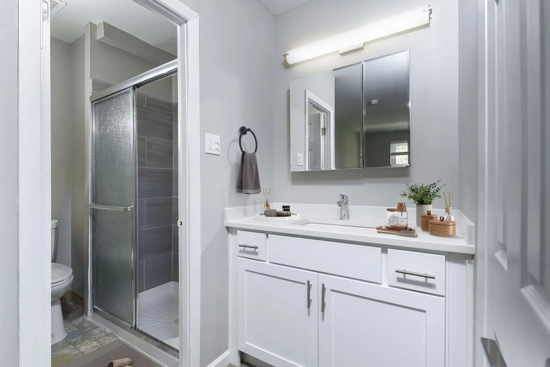 Bathroom featuring a white vanity, large mirror, and glass-enclosed shower at The Addison, offers townhomes for rent in North Wales near Delaware Valley University.