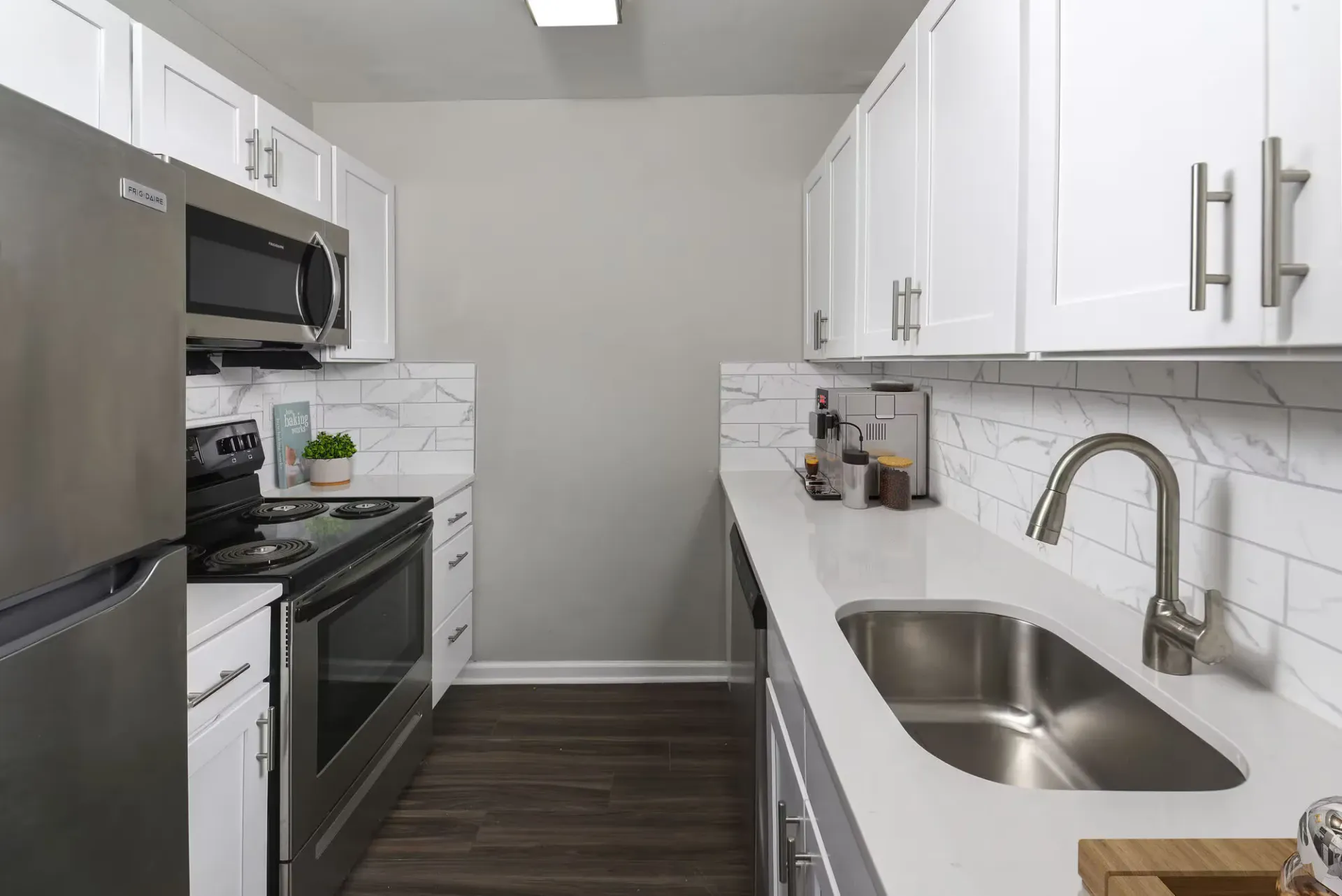 Modern apartment kitchen with white cabinetry, stainless steel appliances, and a large sink at The Addison, offers townhomes for rent in North Wales, PA.