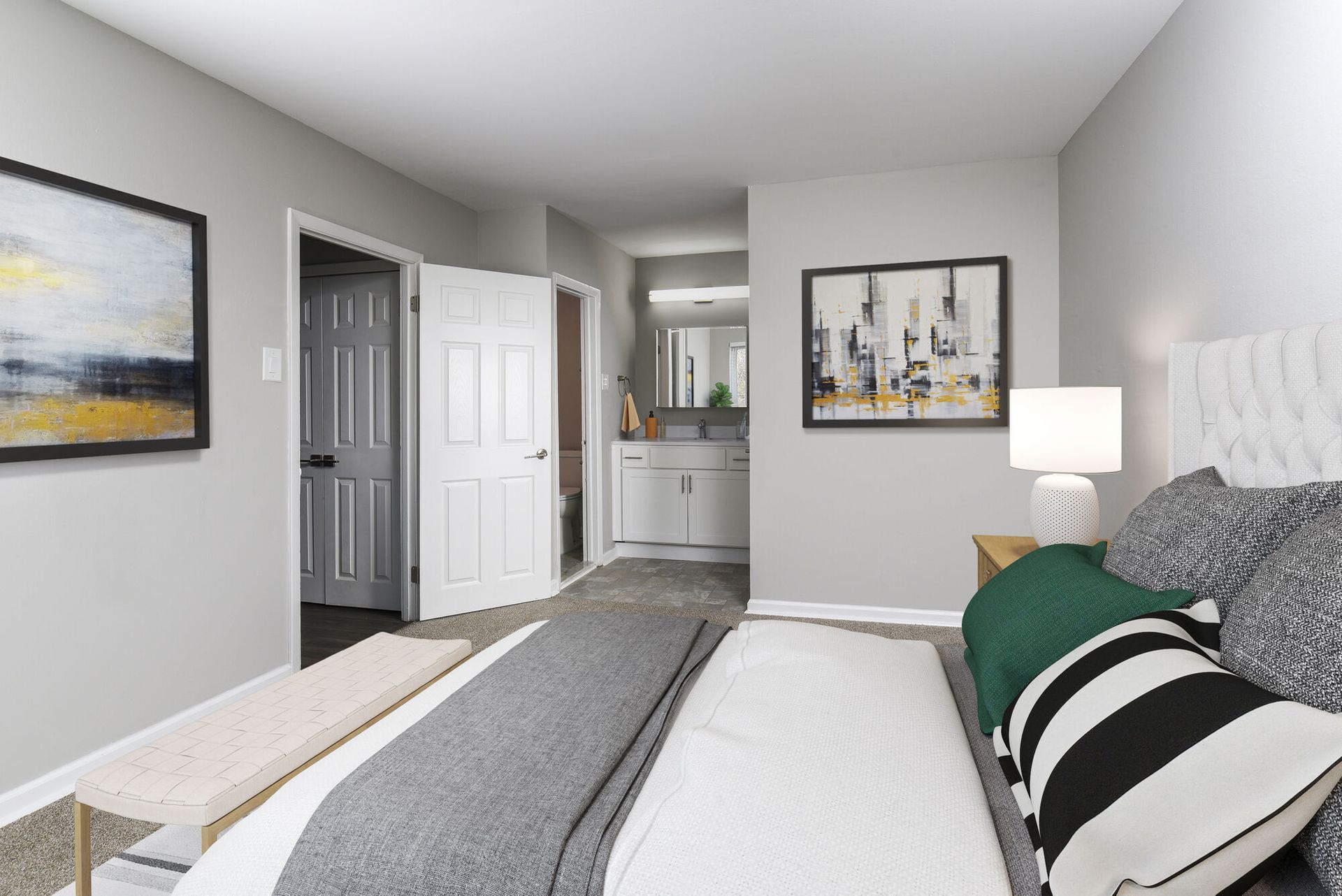Bedroom in a modern apartment with bed, bench, and adjacent bathroom at The Addison, offers apartments for rent in North Wales near Gwynedd Mercy University.
